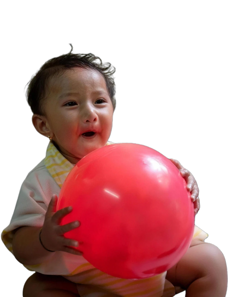 A baby holding a red balloon, from Sewa Foundation’s photo archive